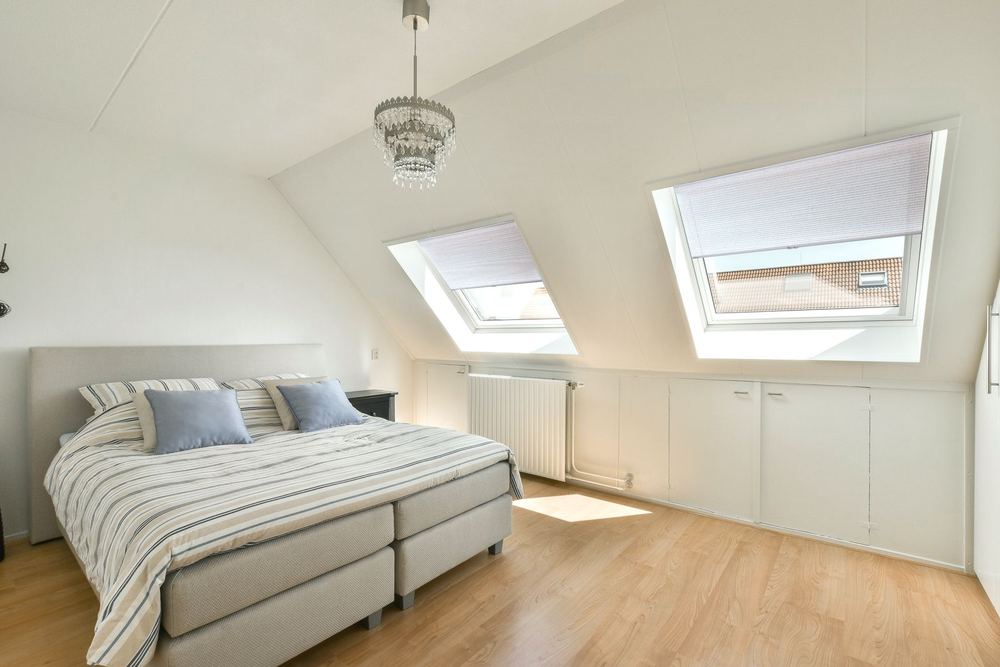 White honeycomb shades on sloped skylight windows in an attic bedroom