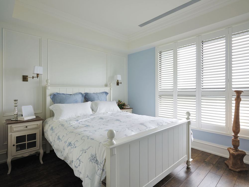 White Normandy® hardwood shutters in a blue and white bedroom