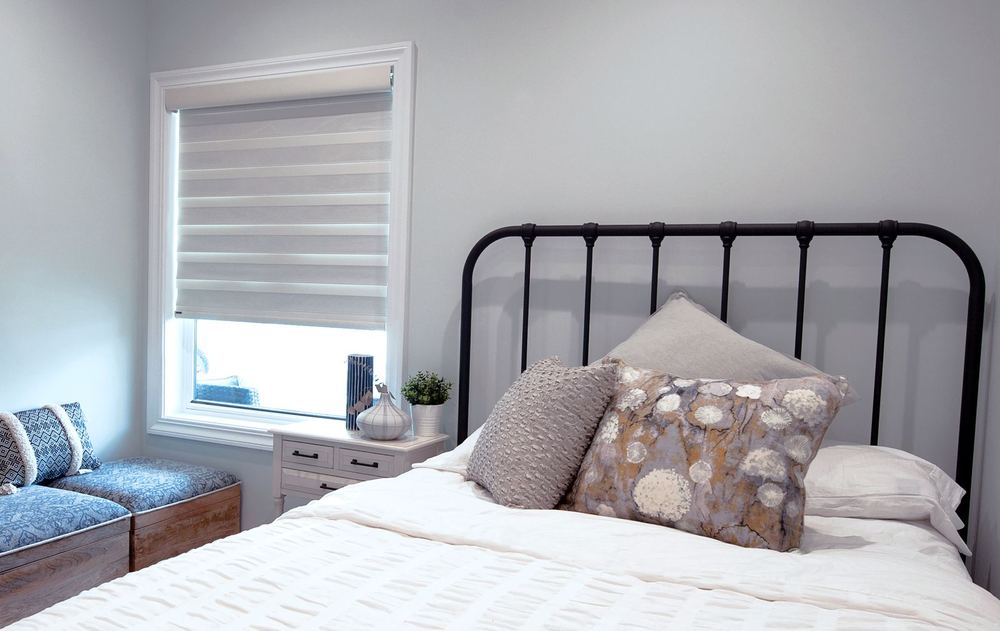 White PerfectSheer™ shade on a bedroom window beside an iron bed frame