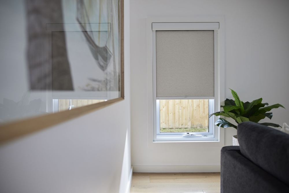 Oatmeal roller shade with a cassette headrail on a small living room window